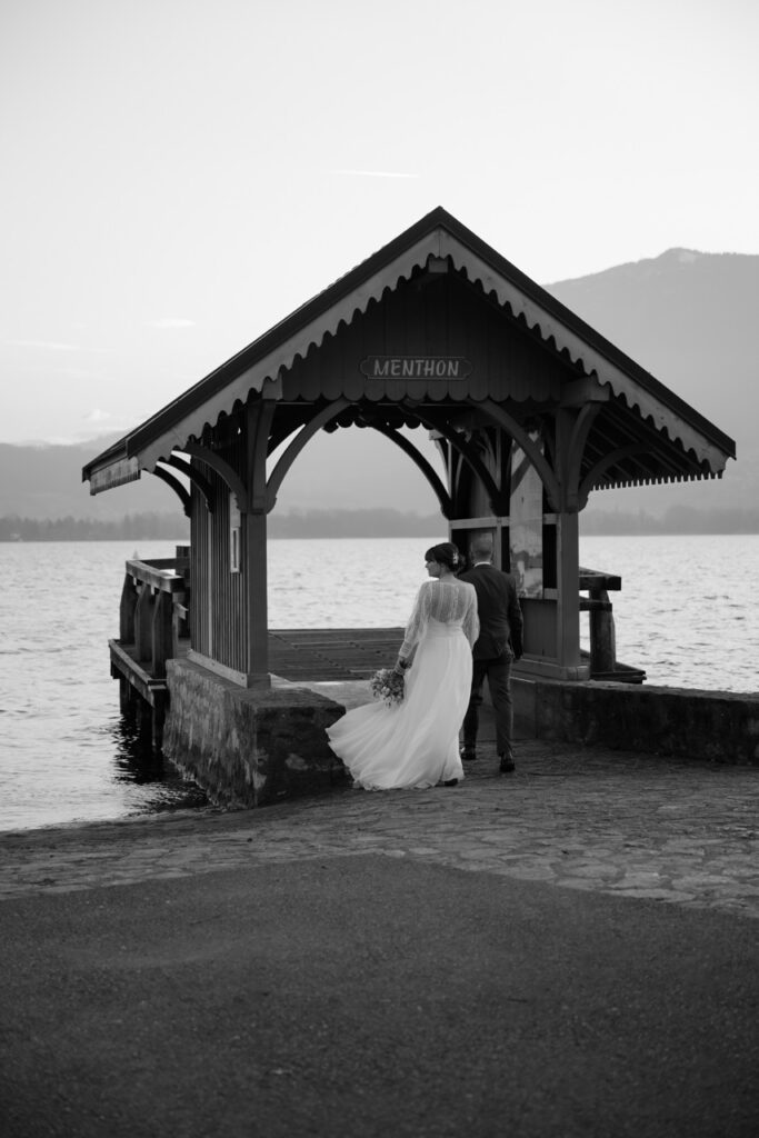 Bride and groom walking into the Menthon boathouse at Lake Annecy, black and white