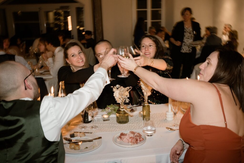 Bride, groom and guests raising glasses for a toast during the wedding dinner