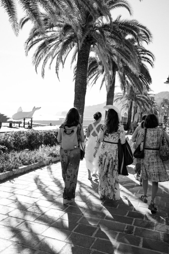 Bride walking to ceremony under palm trees, Finale Ligure Italian Riviera