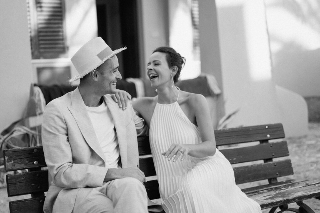 Bride and groom laughing on bench, candid wedding photography Italy